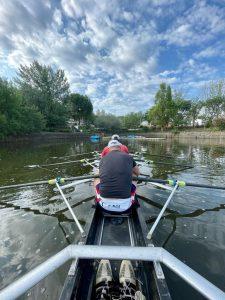 Rowing boat on water, masters rowing crew, boat with river and high white clouds,