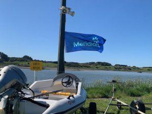 Meridian Energy flag flying off a boat on the Oreti River, NZ
